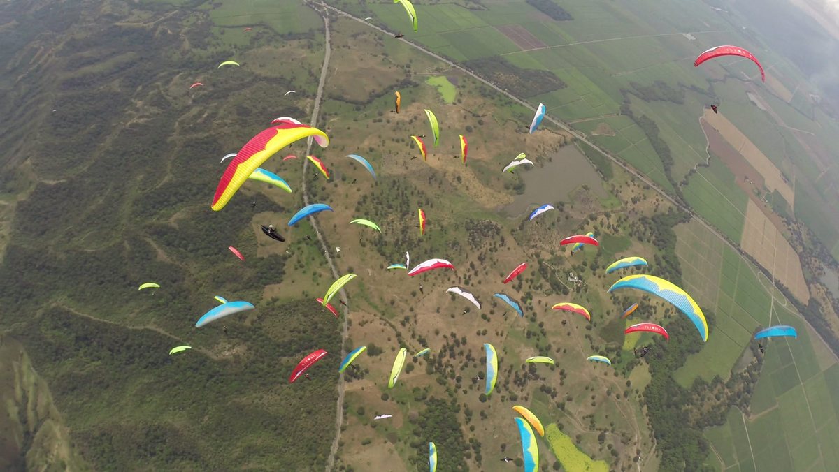 Flock of paragliders circling a thermal over Valle del Cauca, Roldanillo, Colombia. 14th Paragliding World Cup Superfinal.